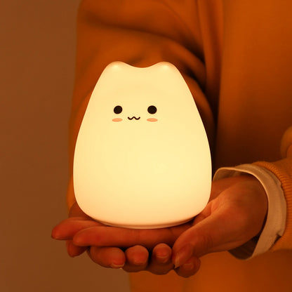 Lámpara infantil con forma de gato encendida, mostrando su luz LED cálida y suave, ideal para crear un ambiente tranquilo en la habitación de los niños.